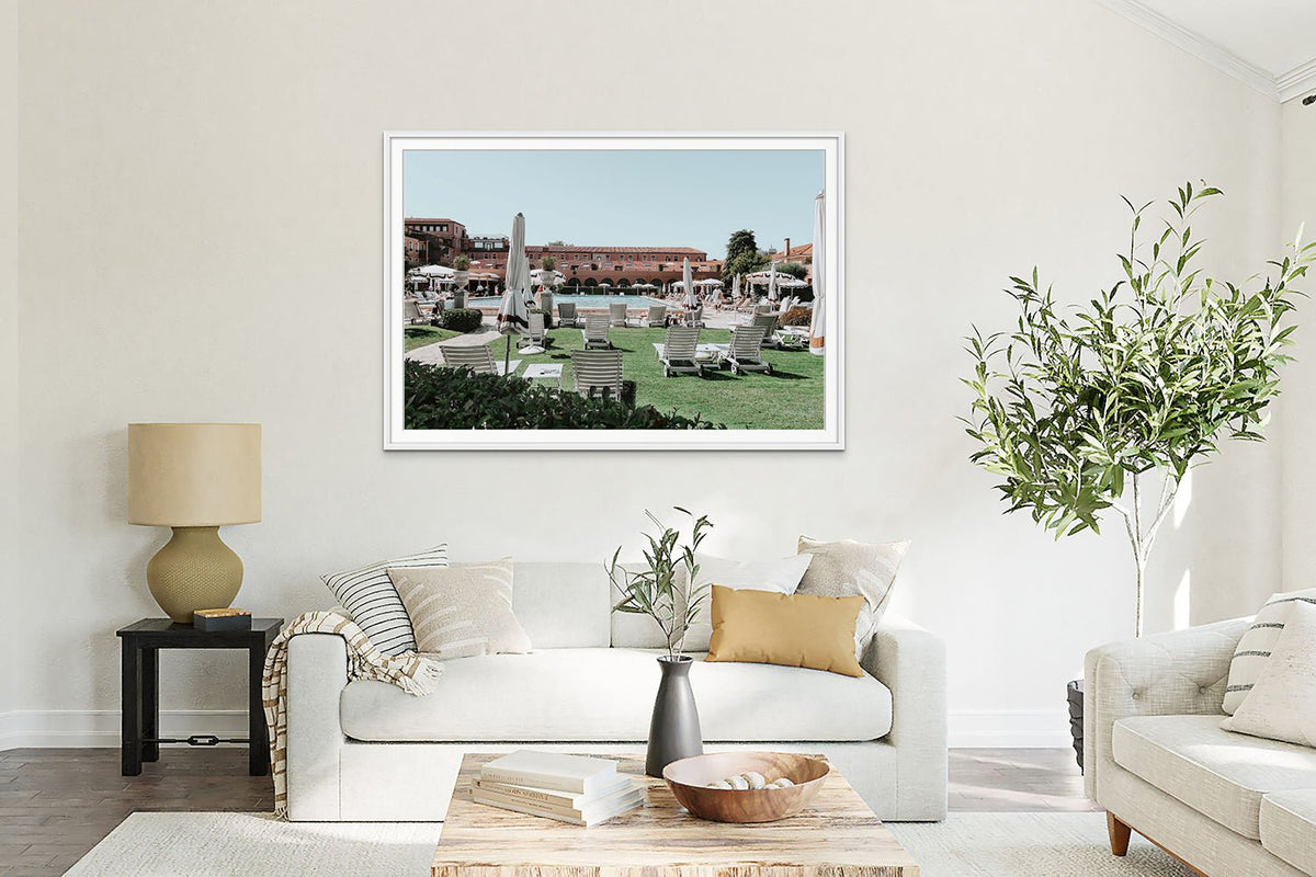 Framed village photograph above a white sofa in a light living room