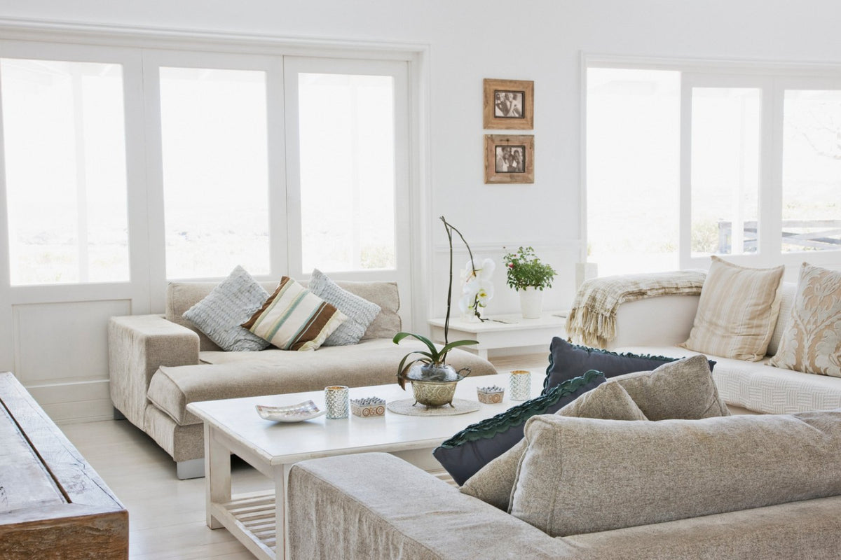 Bright neutral living room with a large white sofa and layered cushions