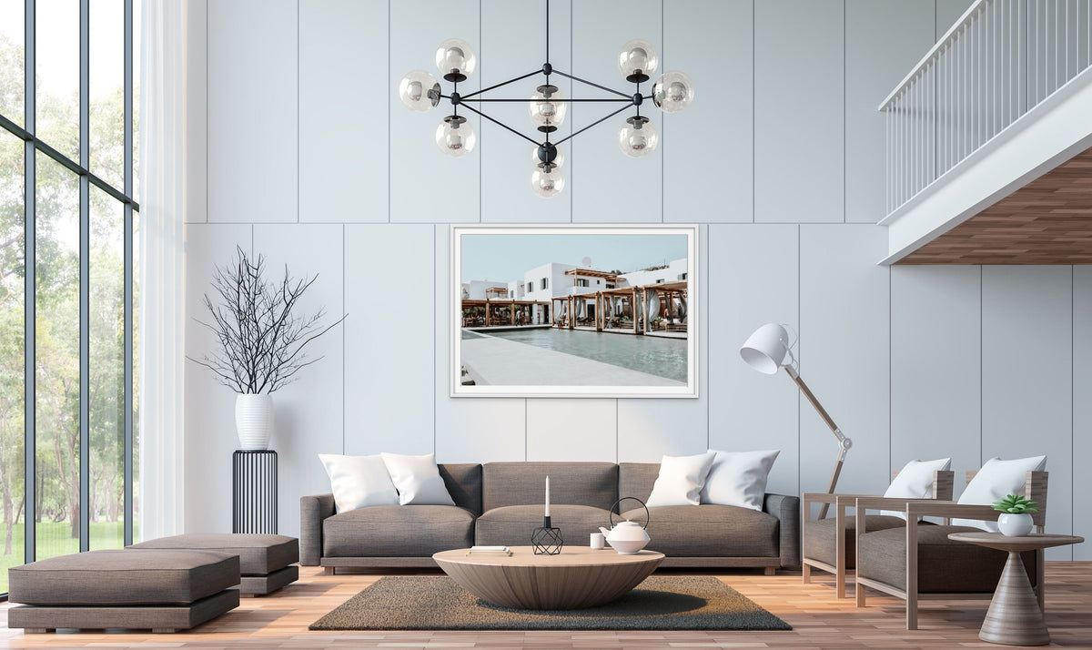 Framed coastal artwork above a grey sofa in a bright modern living room