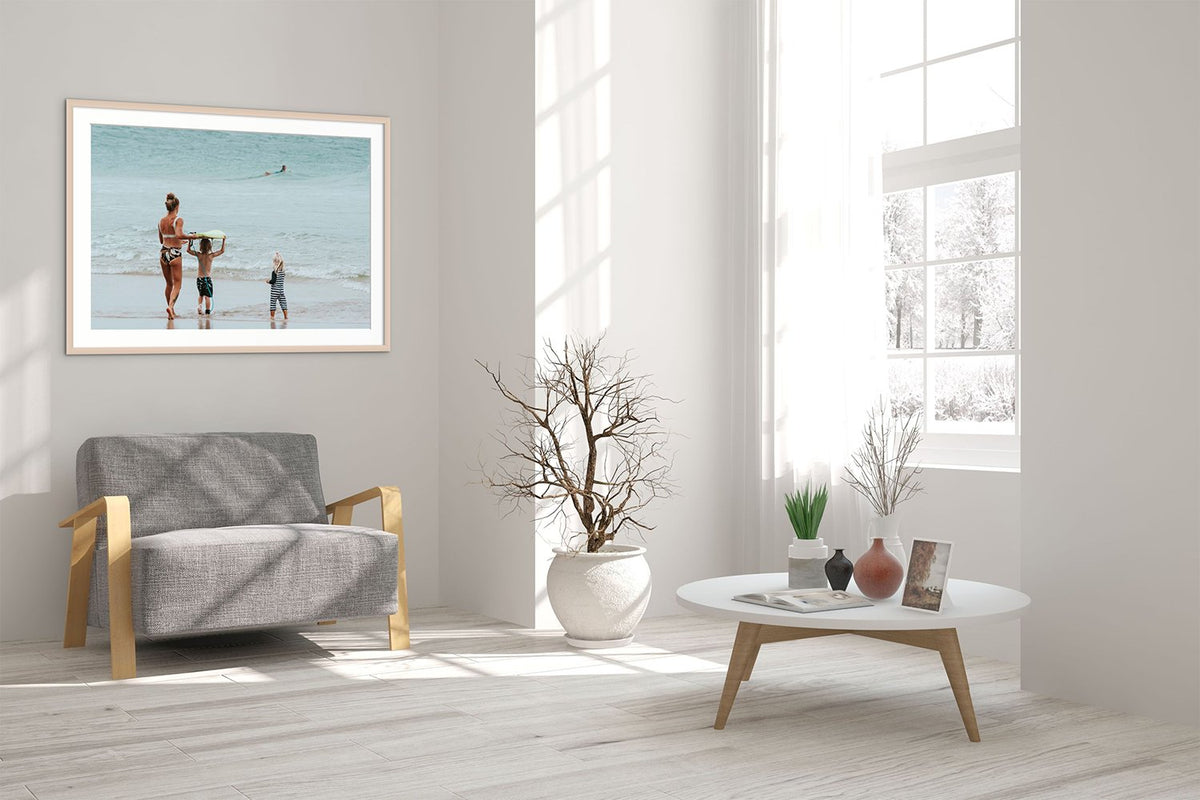 Framed beach photograph above a grey sofa in a bright living room