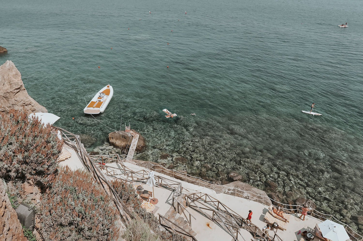 Small boat offshore beside a rocky Mediterranean coastline