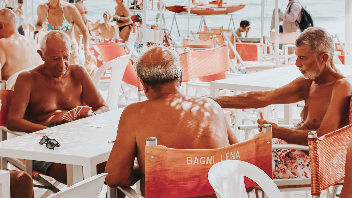 Men playing cards beneath a beach club canopy in Alassio