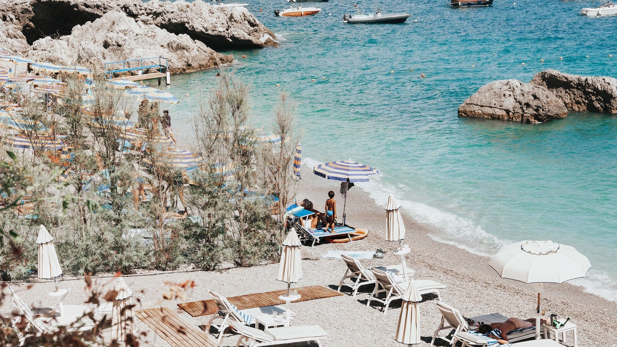 White umbrellas and sun loungers on a turquoise cove on the Amalfi Coast