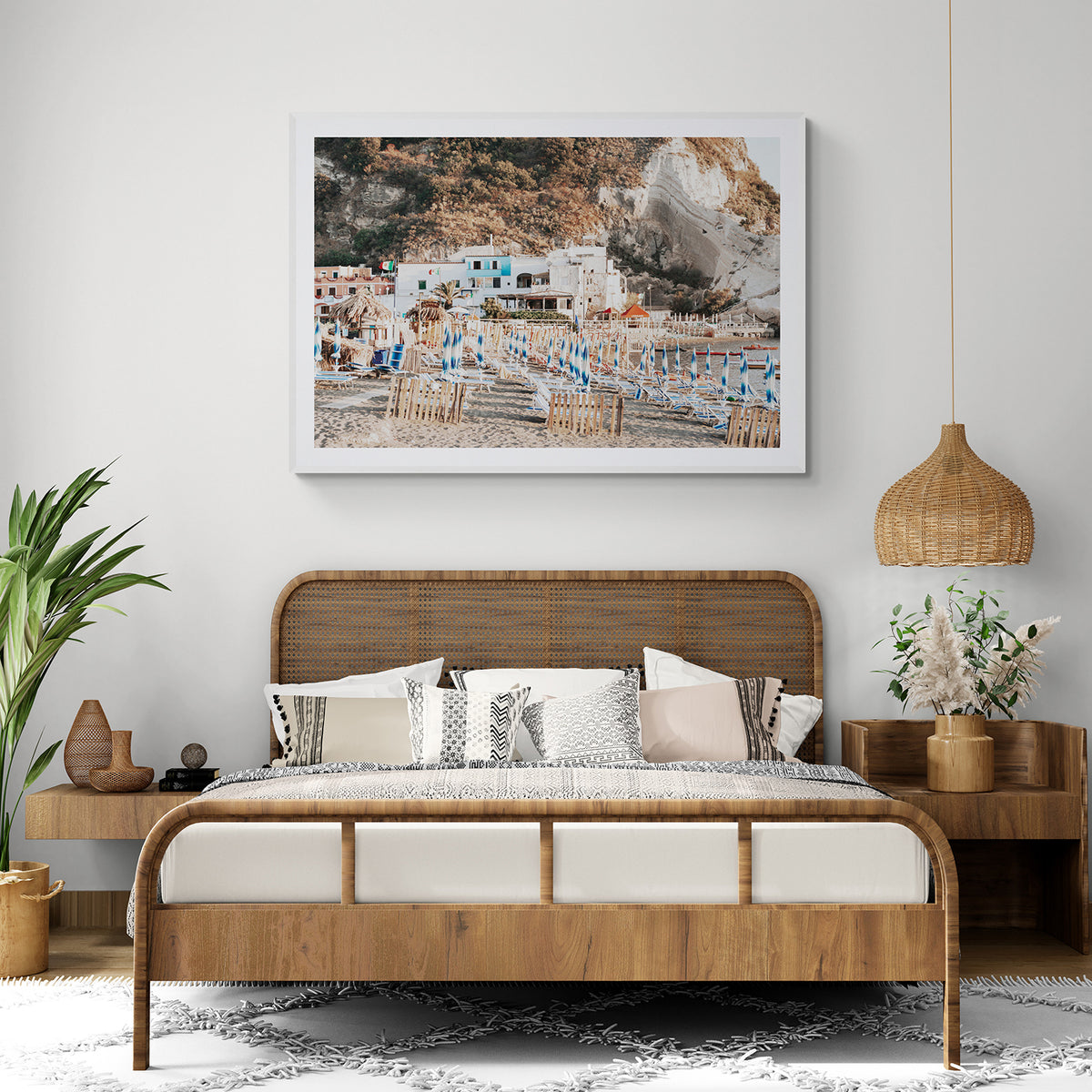 Sant' Angelo Ischia fine art print in a white frame, styled above a rattan bed in a warm, natural bedroom