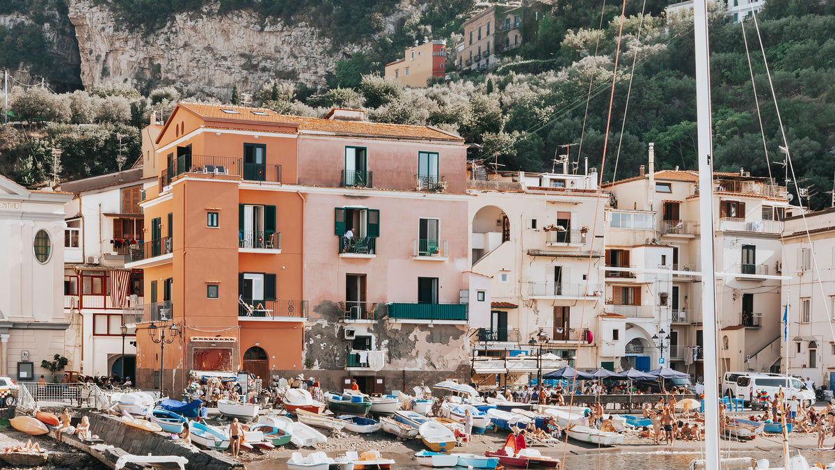 Fishing boats in Marina Grande below the pastel houses and green cliffs of Sorrento