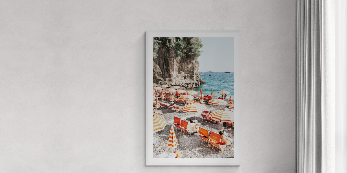 Tangerine Dream fine art print of a Positano beach club in a white frame, styled in a pale room with a linen daybed