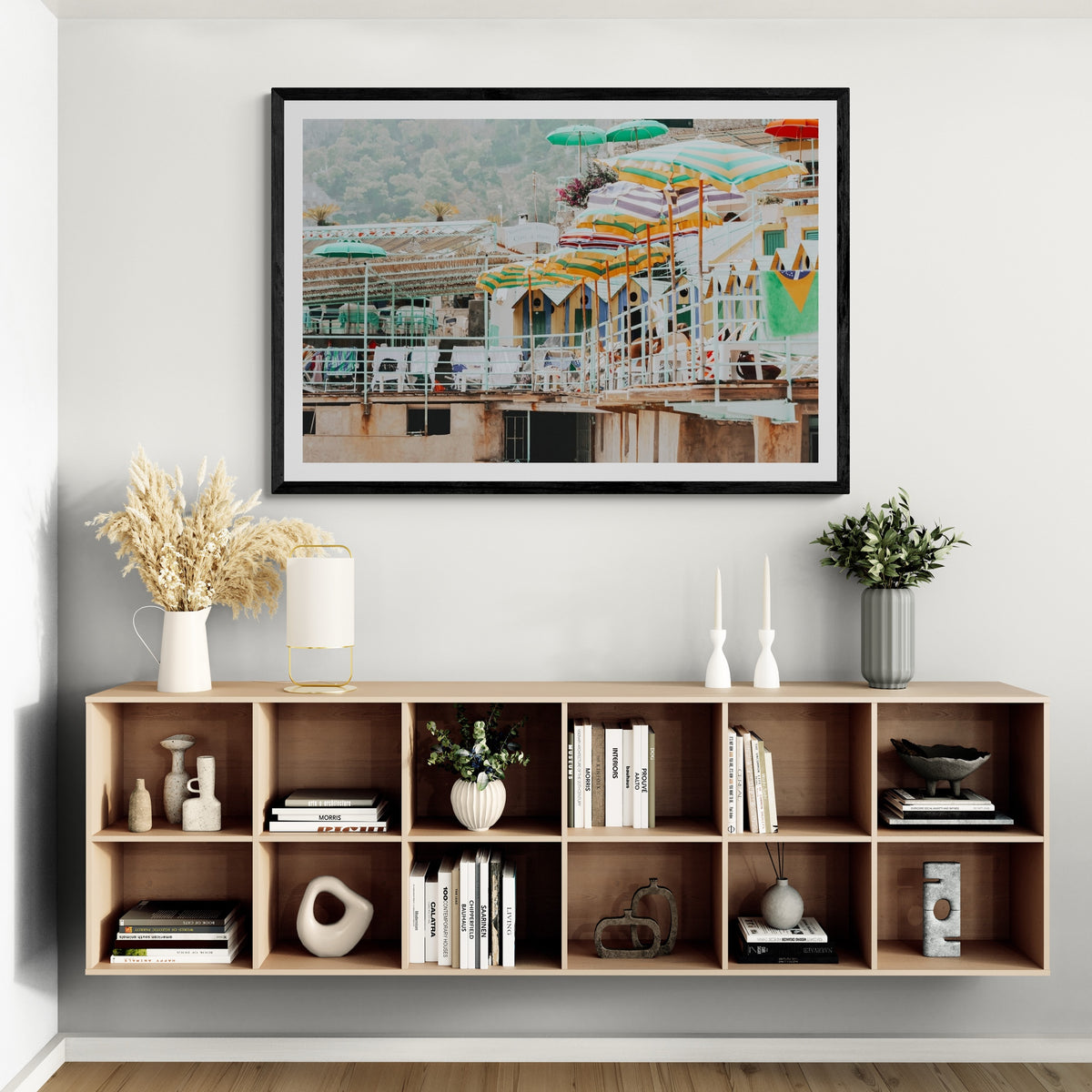 Terrace Tableau Capri, faded striped umbrellas above pastel beach huts on a terrace, framed print styled in a room view 4