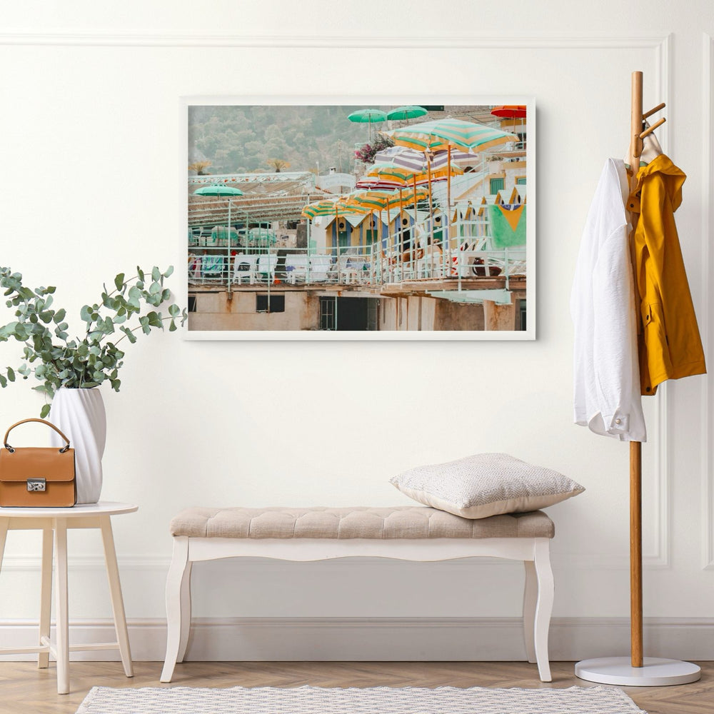 Terrace Tableau Capri, faded striped umbrellas above pastel beach huts on a terrace, framed print styled in a room view 5